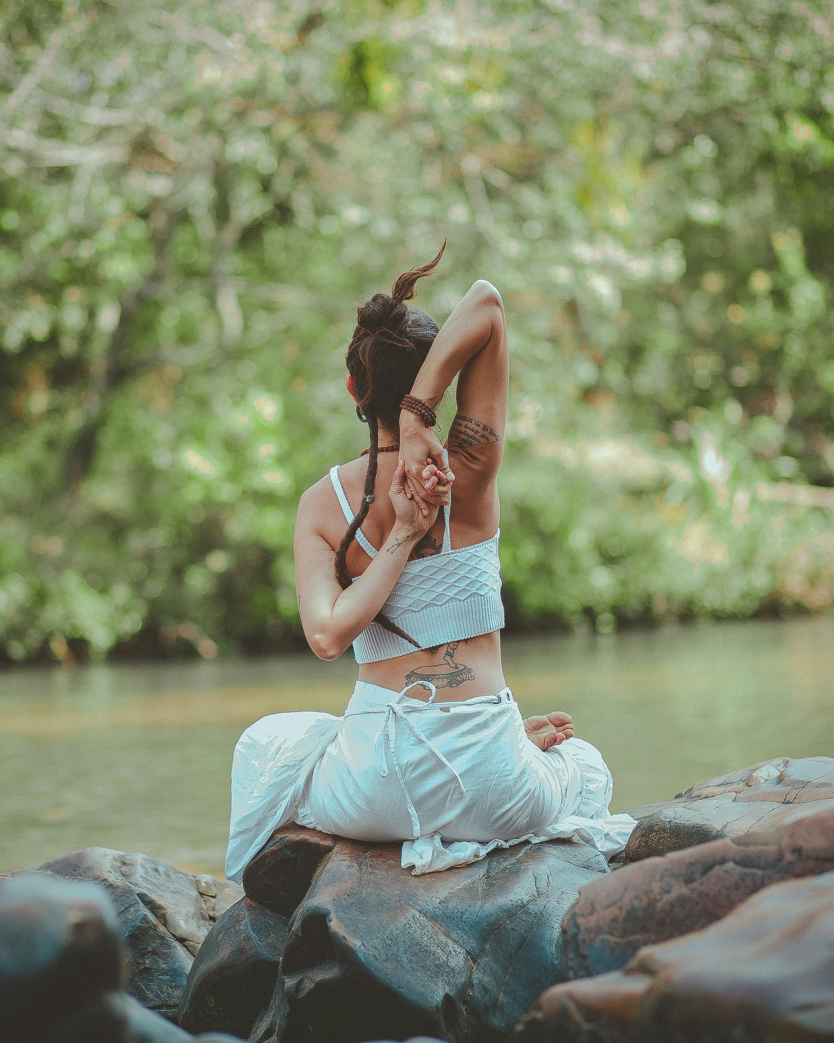 Woman doing yoga by peaceful river — anxiety grounding