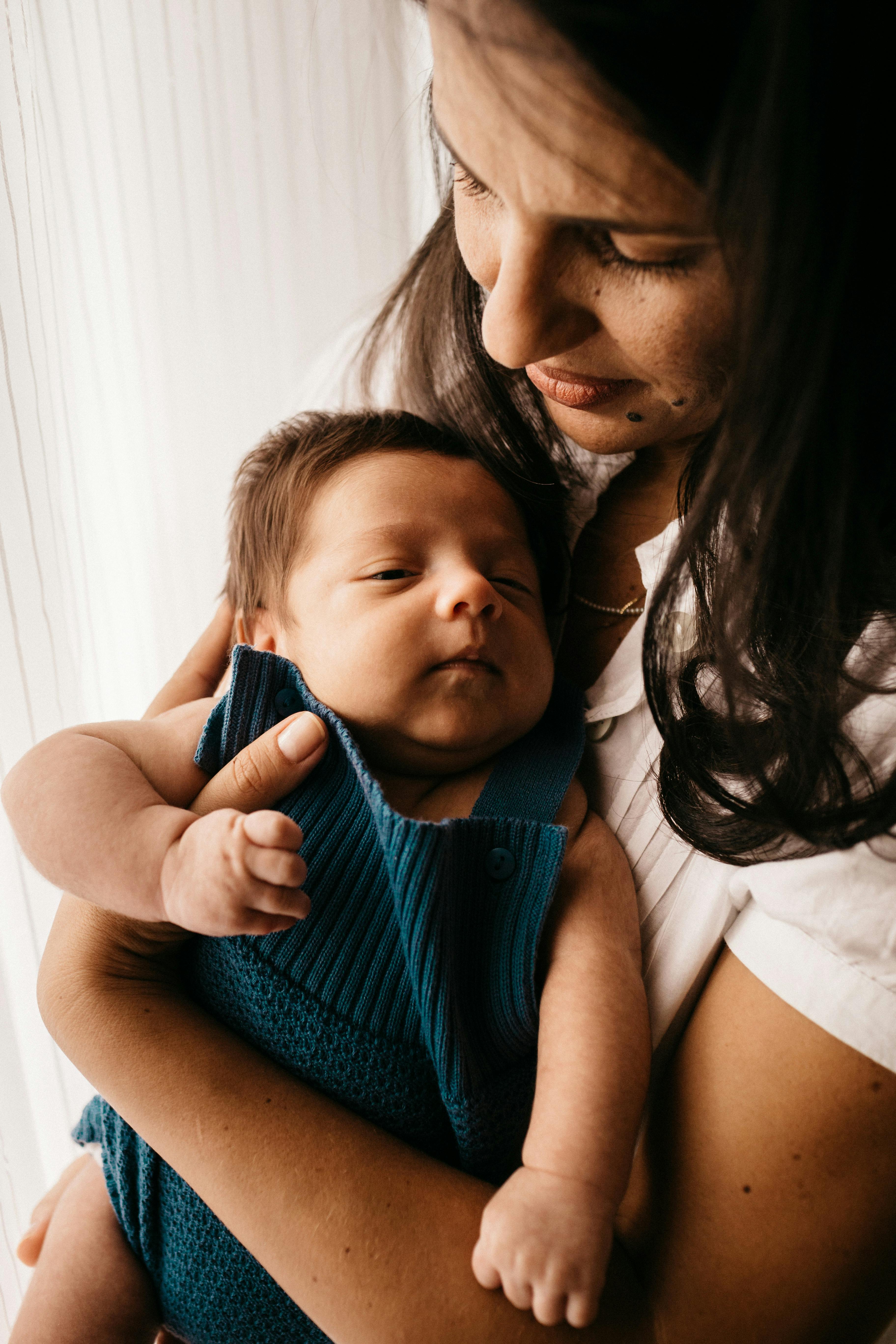 Mother tenderly holding newborn baby — postpartum support